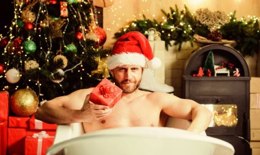 Küvette yatan adam hediye kutusuyla rahatlar. Seksi maço, küvette rahatlıyor. Spa ve sağlık. Kendimi şımartıyorum. Tatiller rahatlatır. Noel turu konsepti. Yeni yıl kutlamalarının tadını çıkar. Kitap otelde kalır..