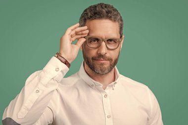 Gözlüklü, görme sorunu olan olgun bir adamın fotoğrafı. Mavi arka planda izole edilmiş bir adamın görüşü. Stüdyoda görme yeteneği olan olgun bir adam. İnsan gözü, gözlük takar.