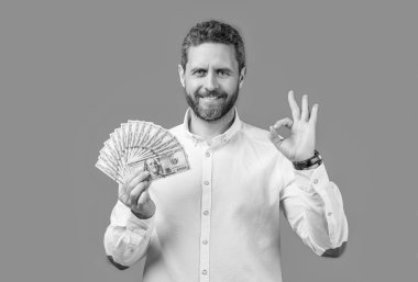 businessman earning money show ok in studio. businessman hold money earning. photo of businessman holding earning money. businessman earning money isolated on blue background.