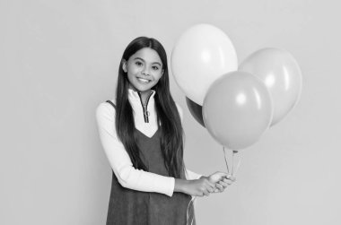 smiling girl with party colorful balloons on yellow background.