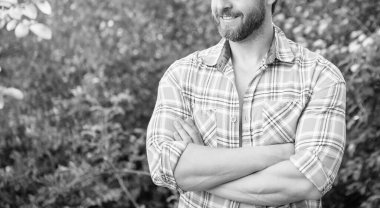 Kareli tişörtlü adamın kırpılmış görüntüsü. Sakallı, beyaz bir adam. Olgun adam dışarıda..