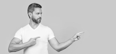 Sıradan gömlekli sakallı adam sarı arka planda izole edilmiş birini işaret ediyor. Stüdyoda sıradan bir adam. Beyaz gömlek giyen beyaz bir adamın fotoğrafı. Sıradan giyinen bir adam..