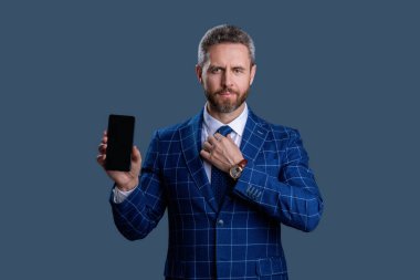 İspanyol iş adamı telefon ekranını sunuyor. Griler 'de izole edilmiş bir telefon gösteren bir iş adamı. Takım elbiseli adam. Yeni telefon uygulaması. Ürünü sunuyorum. İş uygulamasının reklamı. İnternette çalış.