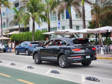 Miami Beach, Florida USA - 5 Haziran 2024 Bentley Bentayga Miami Beach Ocean Drive Caddesi. Blue Bentley Bentayga okyanus yolculuğunda