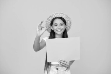 Mutlu genç kızın elinde sarı arka planda fotokopi alanı olan boş bir reklam kağıdı var. Tamam.