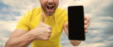 Akıllı telefon ekranı ile fotokopi alanı sunan adamın kırpılmış görüntüsü. başparmak yukarı.