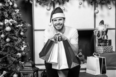 Noel Baba şapkalı mutlu bir genç adam ve noel çantası. Stüdyoda elinde kırmızı Noel çantası olan bir adam var. Noel tatilinde Noel Baba. Mutlu Noeller..