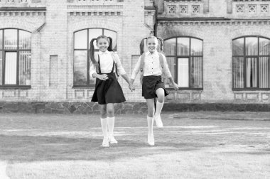 two teen children in uniform walking together outdoor.
