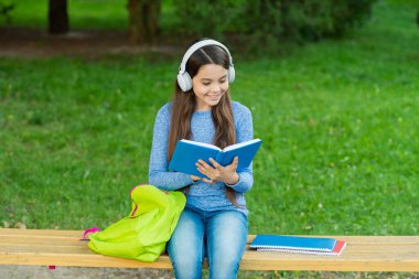 Eğitim ve bilgi. Kızım sesli kitap dinle ve kitap oku. Audiobook kitaba karşı. Öğrenci kız. Okul eğitimi. Liseli kız dışarıda kitap okur ve sesli kitap dinler. Okula geri dön..