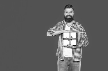 Gri arka planda hediye kutusu olan olgun sakallı hippi..