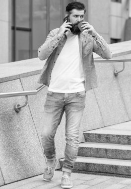 Açık havada akıllı telefondan konuşan uzun boylu bir adam. Adam dışarıda akıllı telefondan konuşuyor. Adam sokakta akıllı telefondan konuşuyor. Akıllı telefondan konuşan adamın fotoğrafı..