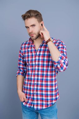 Adam gri renkte izole edilmiş kulaklık kullanıyor. Modern kablosuz kulaklıklar. Elsiz kulaklık. Kulaklık cihazı aksesuarı. Kablosuz kulaklık cihazı. Aletli adam. Kablosuz kulaklıklı bir adam. Kulaklık Kullanımı.