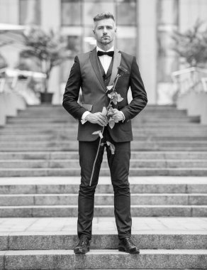 Aşk günü konsepti. Dışarıda duran aşk dolu smokinli adam. Aşk günü için çiçek hediyesi..