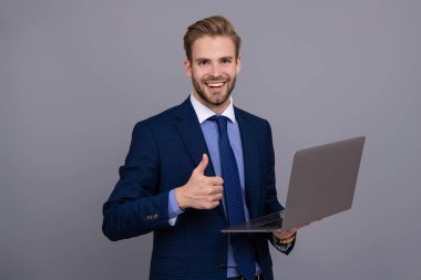 Çevrimiçi çalışan serbest çalışan biri. Adamın online blogu var. Ofisinde dizüstü bilgisayarla takım elbiseli bir iş adamı. Uzaktan kumandalı çalışıyor. İş blogu başarısı. Grey 'de izole edilmiş dizüstü bilgisayar kullanan bir iş adamı. Başparmak yukarı..