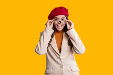 Moda tarzı şaşırmış bir kız. Gözlüklü ve bereli sonbahar kızı. Sonbahar renk paleti. Sonbahar sezonu. Sonbaharda tarz sahibi bir kız. Gençlik modelinin sonbahar havası. Sonbahar kızı sarıda izole edilmiş.