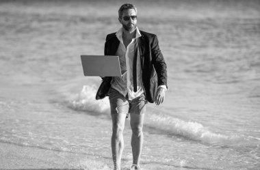 Uzaktan kumanda çalışıyor. İş adamı plajda rahatlar. Yazın dizüstü bilgisayarı olan takım elbiseli bir iş adamı. İş adamı yazın denizde iş yapmayı hayal eder. Saf rahatlama deneyimi. Kumsalda dinlenen bir iş adamı..