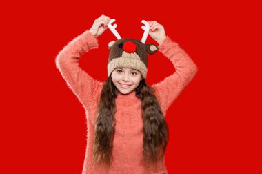 Winter fashion for teenage style. Girl in knitted hat in winter season. Childhood lifestyle. Winter child wardrobe. Teenage girl in Xmas hat isolated on red. Earflap detailing. clipart