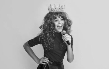 Sarı arka planda mikrofonu olan tacın içindeki mutlu çocuk..