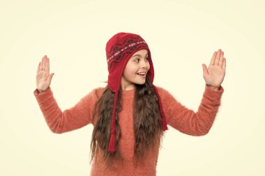 Sıcak şapkalı genç kız beyaz arka planda izole bir şekilde ellerini havaya kaldırdı. Genç kız stüdyoda süveter ve kalın bir şapka giyer. Genç kızlar için kış modası. Sıcak şapka örgüsü. Sıcak şapkalı genç kız..