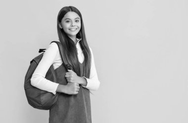 child smile with school backpack on yellow background.