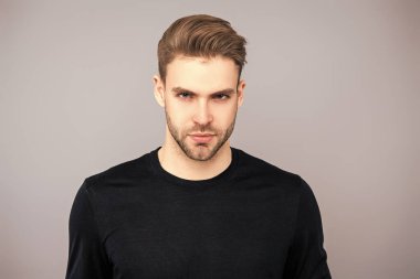 Erkek derisi. Adamın şık bir saç kesimi var. Moda saç stili olan bir adam. Sıradan erkek tarzı. Beyazlı genç bir adam gri yolda izole edilmiş. Kendine güvenen adam portresi. Erkeklerin cilt bakımı. Manyetik Bakış.