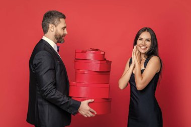 Kırmızıda izole edilmiş zarif bir çift. Hediye değişimi. Birlikte romantik bir gün. Yıldönümü için aşk hediyesi. Sevgililer Günü. Çift Sevgililer Günü 'ne hediye veriyor. Erkek kadına hediye. En iyi sürpriz..