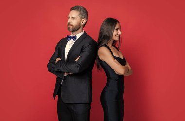 Kadın ve erkek zaman zaman çıkıyorlar. Romantik aşk. Sevgililer Günü. Zarif giyimli bir çift. Resmi erkek ve kadın. Çift poz veriyor. Kırmızıda izole edilmiş resmi kıyafetli zarif bir çift. Moda tarzı.