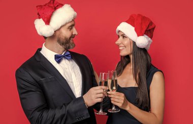 Noel partisini mutlu bir çiftle kutlayalım. Stüdyodaki çifte mutlu Noeller. Çift Noel 'i kutluyor. Tatili kutlayalım. Xmas çifti kırmızı arka planda izole edilmiş şampanyayla kutluyor.
