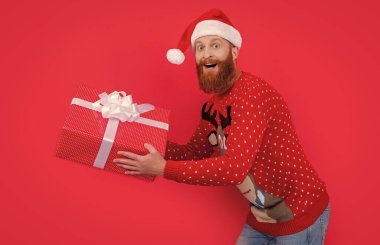 Yeni yıl hediyesiyle şaşırmış bir adam. Yeni yıl indirimi. Noel Baba acele et. Yeni yıl hediyesi kırmızıda izole edilmiş..