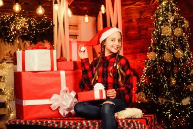 Mükemmel bir Noel hediyesi. Noel ağacındaki neşeli küçük kız. Evi neşeyle süsleyin. Xmas havası. Aile tatili. Mutlu yıllar. Kırmızı Noel Baba şapkalı çocuk. Elinde hediye kutusu olan çocuk. kış alışverişi.