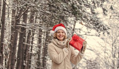 Hazır mısın? Herkese mutlu noeller dilerim. Yeni yılınız kutlu olsun. Noel tatili. Hediye zamanı. Kırmızı Noel Baba şapkalı kadın hediye kutusunu tutuyor. Boks günü. Kış alışverişi. hediye ve sürpriz konsept.