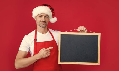 Noel şapkalı ve önlüklü gülümseyen olgun bir adam yazı tahtasında fotokopi alanı ile işaret ediyor..