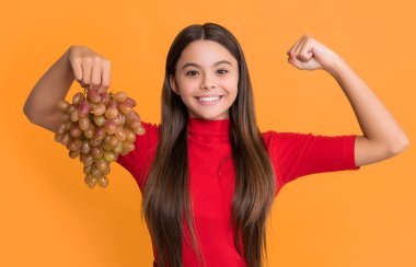 pozitif çocuk taze üzümleri sarı arka planda tutar.
