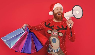 Mutlu noeller. Mutlu adam hoparlörde noel satışları hakkında anons yapıyor. Noel 'de alışveriş çantalı bir adam kırmızıda izole edilmiş..