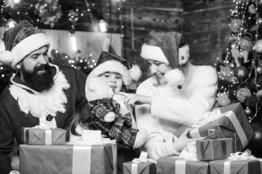 Noel Baba şapkalı küçük bir çocuk ve ailesi. Mutlu noeller. Baba ve anne kızı sever. Kış tatili Alışveriş satışları. Xmas hediye kutuları. Hediyeni aç. Ev dünyanın en güzel yeridir..