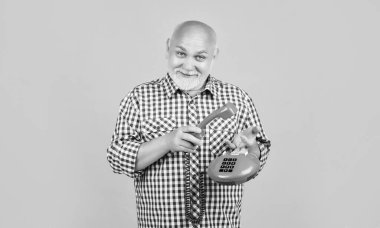 cheerful aged man with retro telephone on yellow background.