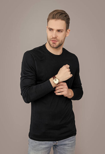 Молодой человек со щетиной в часах изолирован на сером фоне. У кавказца щетина. стильные часы. Человек с щетиной носить наручные часы в студии.