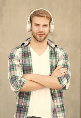 Dışarıda müzik dinleyen bir adam. Müzik dinleyen ve kareli gömlek giyen bir adam. Kulaklıkla müzik dinleyen bir adamın fotoğrafı. Adam açık havada müzik dinliyor..