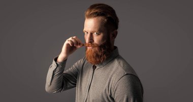 Traşsız adamın stüdyo fotoğrafı. Bıyık ve sakal bakımı. Yakışıklı, sakallı ve bıyıklı. Gri arka planda sakallı ve bıyıklı traşsız bir adam..