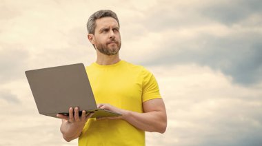 Bilgisayarda çalışan bir adam gökyüzü arka planında. Boşluğu kopyala.