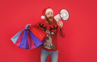 Sakallı Noel Baba elinde alışveriş torbalarıyla megafona bağırıyor. Noel arifesi alışverişi. Noel indirimi duyurusu yapıyorum. Tatil indirimi duyurusu. Mutlu noeller. Mutlu yıllar..