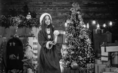 Noel tatili. Noel zamanı geldi. Gelmiş geçmiş en iyi hediye. çocukluk mutluluğu. Noel Baba kostümü giymiş neşeli bir çocuk. Çocuklar Xmas 'ı sever. Küçük mutlu kız hediye kutusunu tutuyor. Yeni yıl partisi kutlaması.