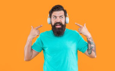 Hippi kulaklıklı adam müzik dinliyor. Kulaklıklı hipster adamın stüdyo fotoğrafı. Müzik dinliyordum. Modern erkek aleti. Kulaklıkla müzik dinleyen hippi adam sarıda izole edilmiş..