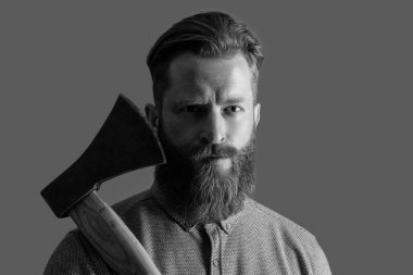 Keskin baltalı sakallı berber adamın kızıl sakalı var. Stüdyodaki sakallı berber. Berber konsepti. Kızıl sakallı sakallı sakallı adam gri baltayı soyutladı..