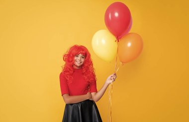 Sarı arka planda parti balonuyla gülümseyen genç kız..