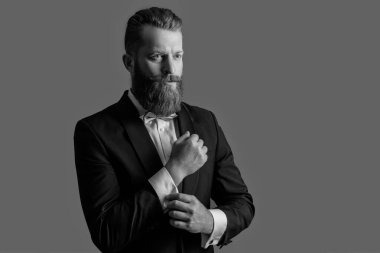 Zarif iş adamı kelepçeleri ayarlıyor. Smokin giyen sakallı iş adamı. Resmi kıyafet giymiş sakallı bir iş adamı. Kızıl saçlı İrlandalı adam stüdyosu Gri, kopyalama alanında izole edildi.