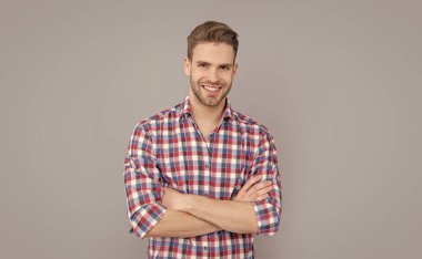 Gri arka planda kareli gömlekli mutlu yakışıklı bir adam. Gündelik tarzda bir adam. Stüdyo fotoğrafı. Beyaz adamın sakalı var..