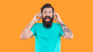 Şaşkın DJ 'in kulaklıklarıyla müzik. Kulaklıklı adam sarı arka planda izole edilmiş. Stüdyoda müzik kulaklığı takan DJ. Adam DJ kulaklıklarıyla müzik dinliyor..