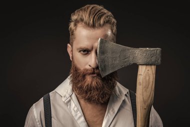 Siyaha izole edilmiş baltalı askılı vahşi bir adam. Saçları kızıl saçlı, olgun bir adam. Acımasız erkek modası. Erkek vahşeti. Antika pantolon askılı, eski tip bir gaddar adam. Düzgün bak..
