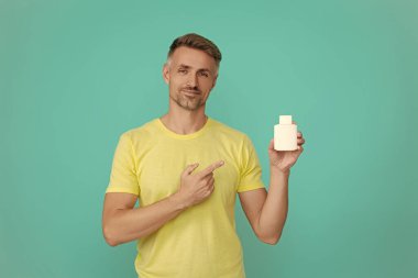 Maviye izole edilmiş multivitamin ve vitamin takviyesi veya ilaç sunan olgun bir adam..